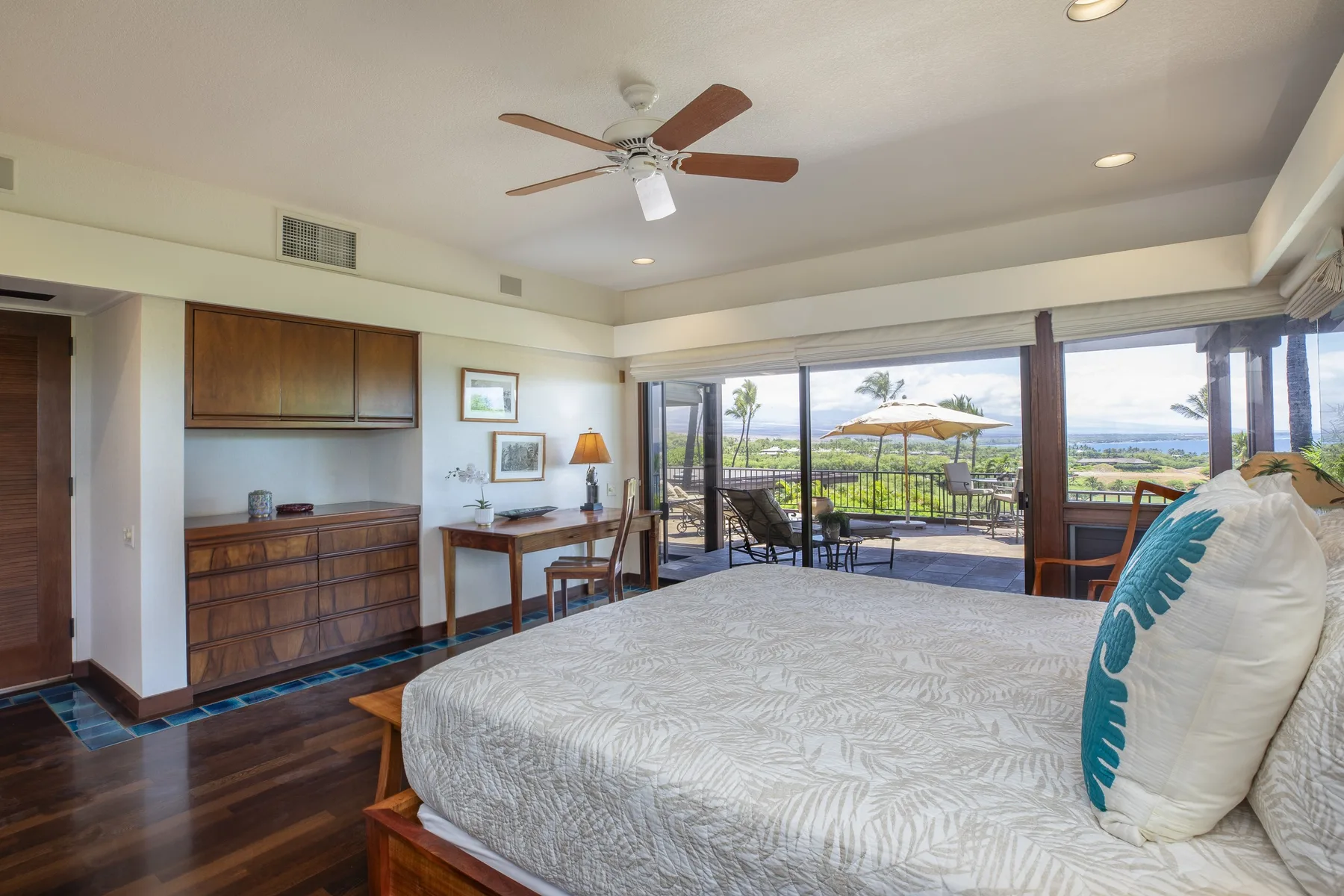 A bedroom with a bed, wooden furnishings, and sliding doors opening onto a balcony.