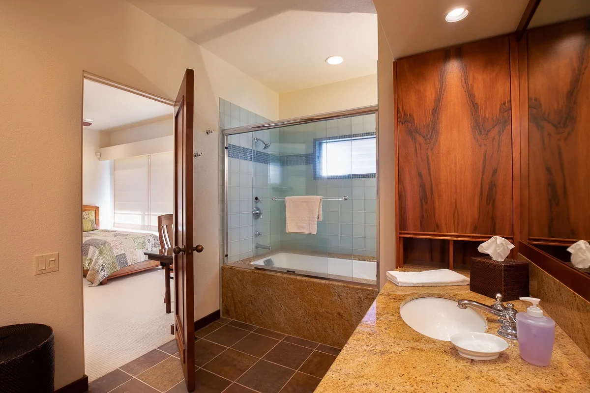A bathroom with a glass shower and a sink beside a wood vanity.
