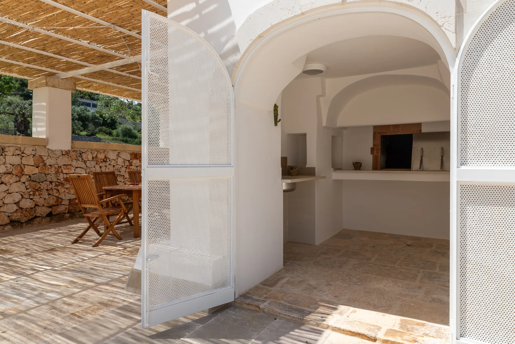 An arched entrance opens onto an interior room, with wooden seating on the patio.