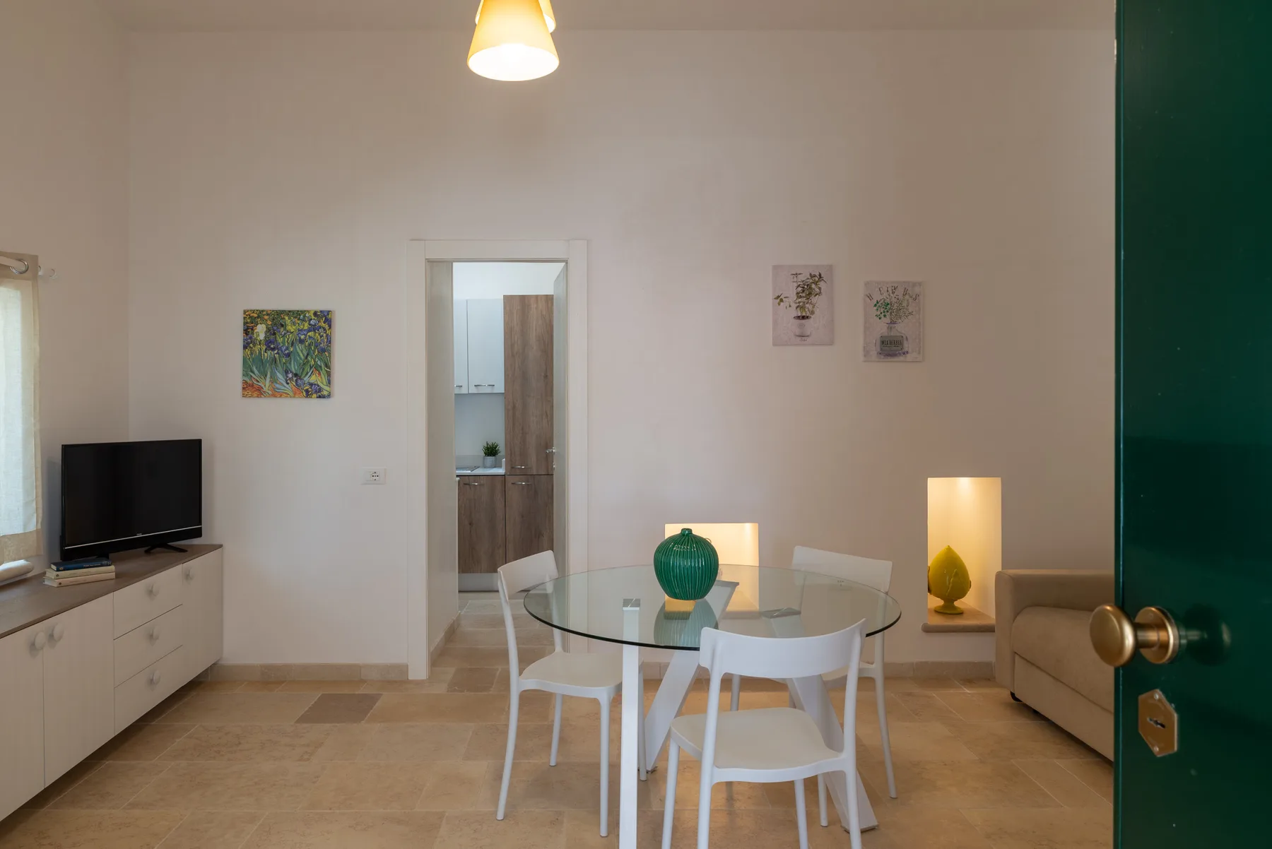 A dining area with a glass table and white seating, beside a living room.