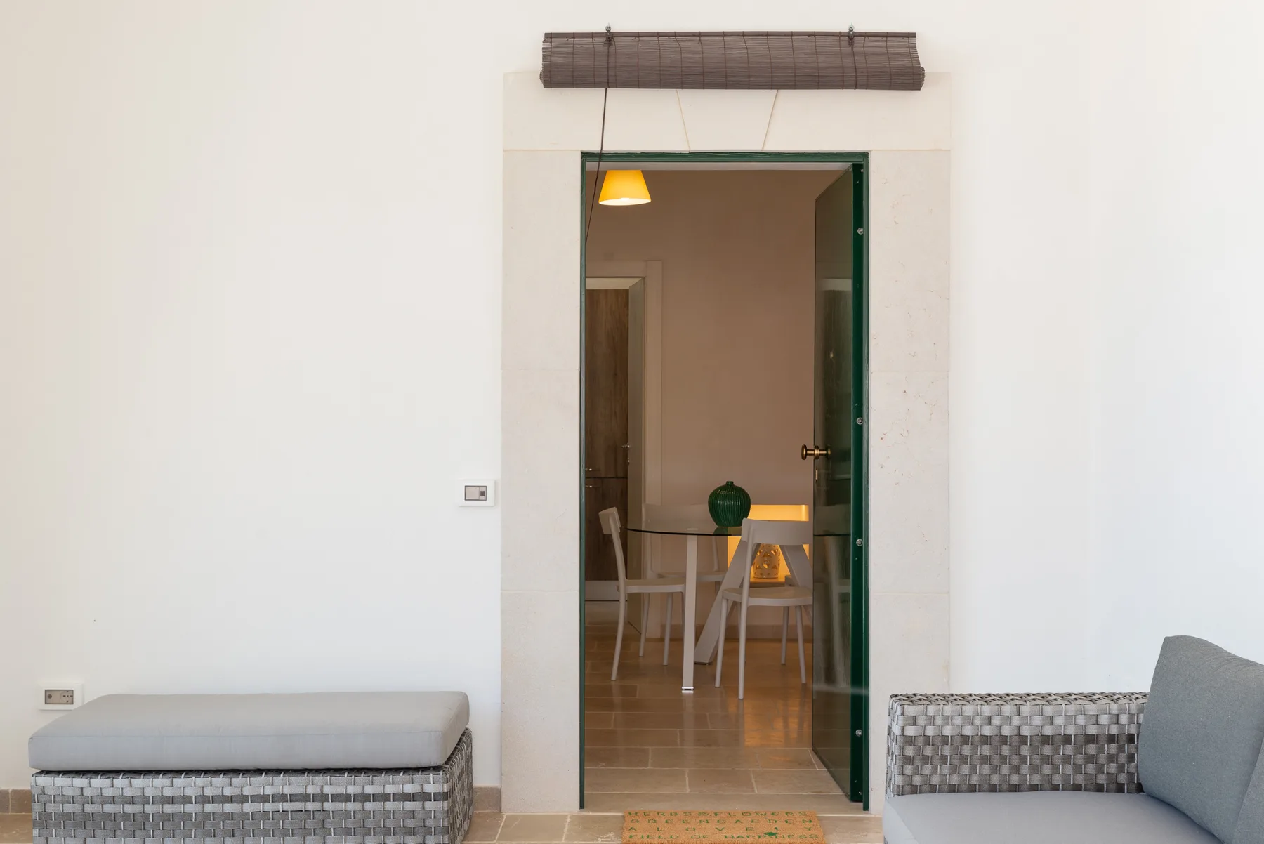 A doorway opens from a bright room into a dining area with a table and chairs.