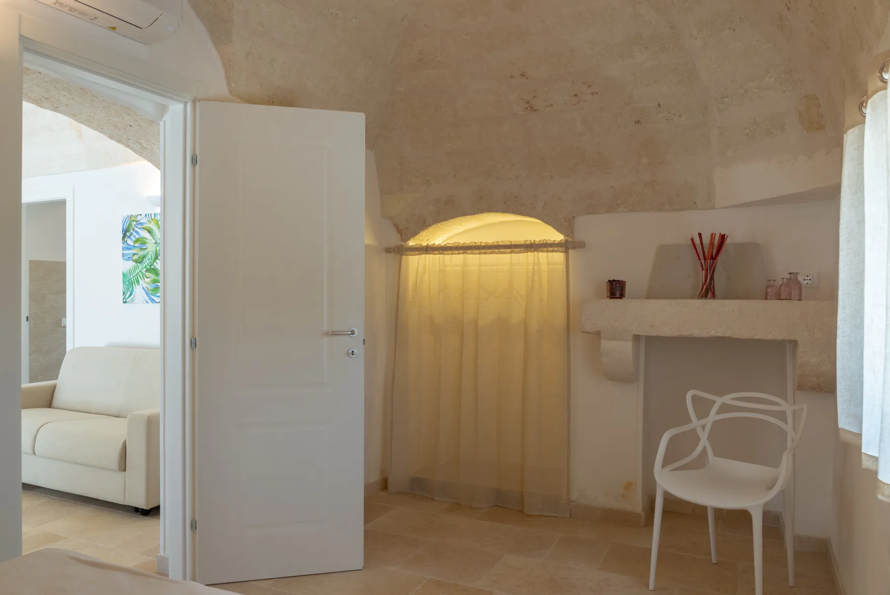 A bright room with an open door, a curtained alcove, and a desk.