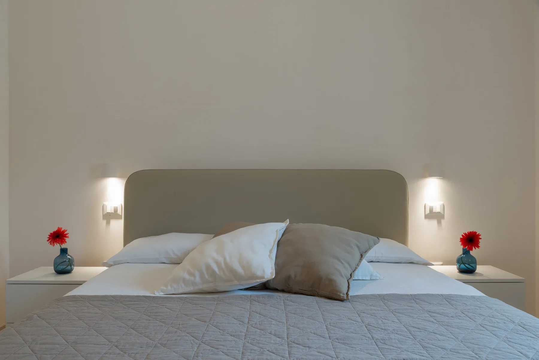 A bedroom with a bed, layered pillows, and matching bedside lamps.