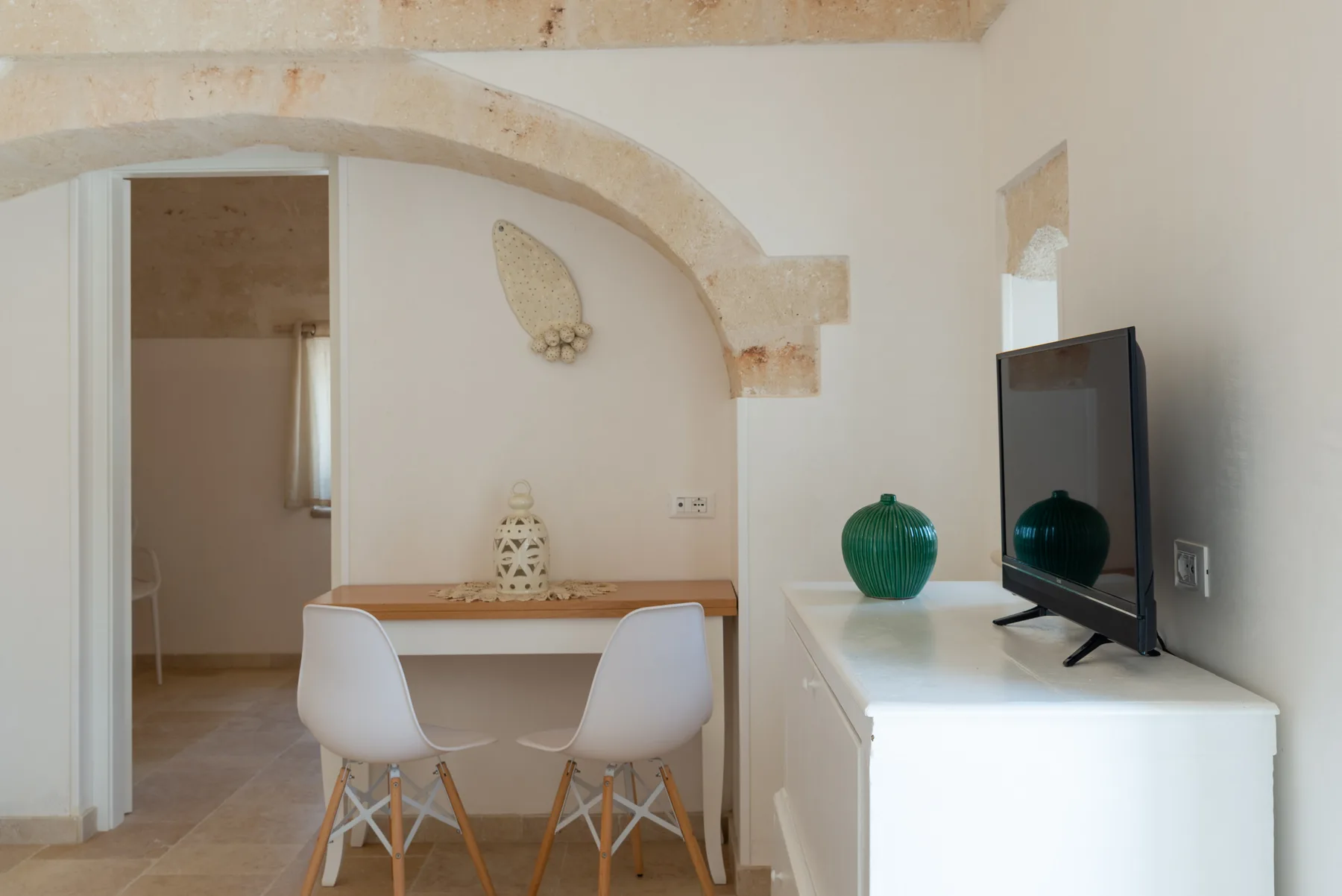 A bright dining area with a table and chairs beneath a stone arch.