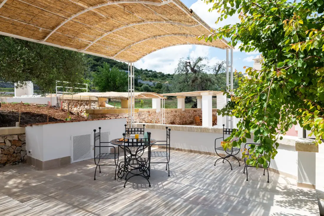An outdoor terrace with a table and seating beneath a woven canopy.