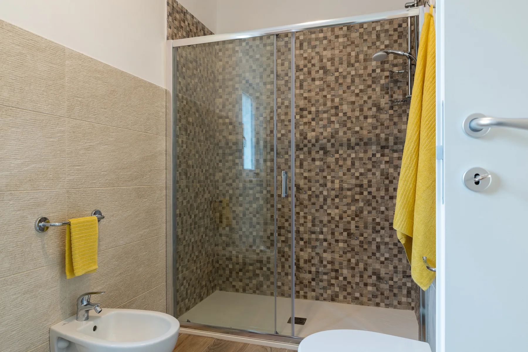 A bathroom with a glass shower and a small sink.