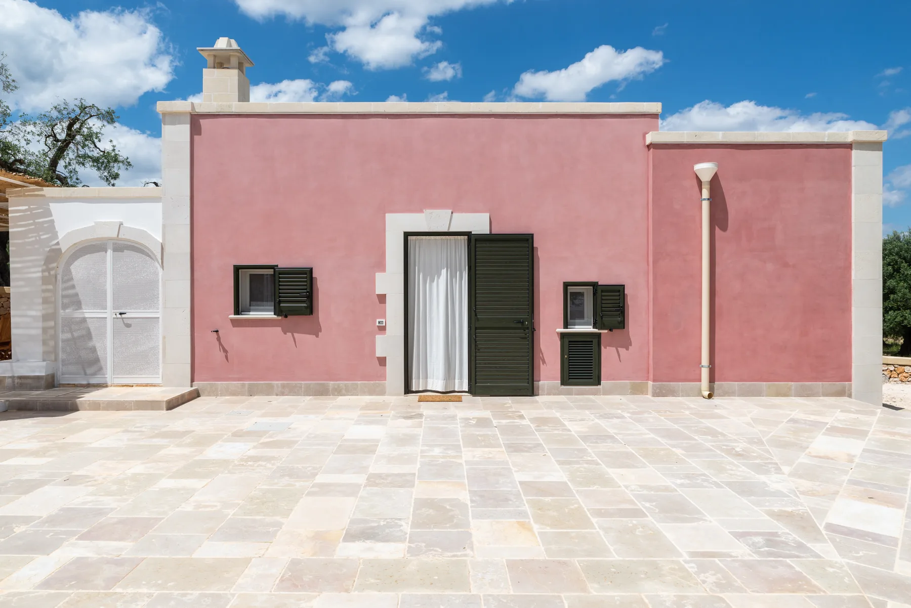 A pink stucco building opens onto a broad stone-paved courtyard.