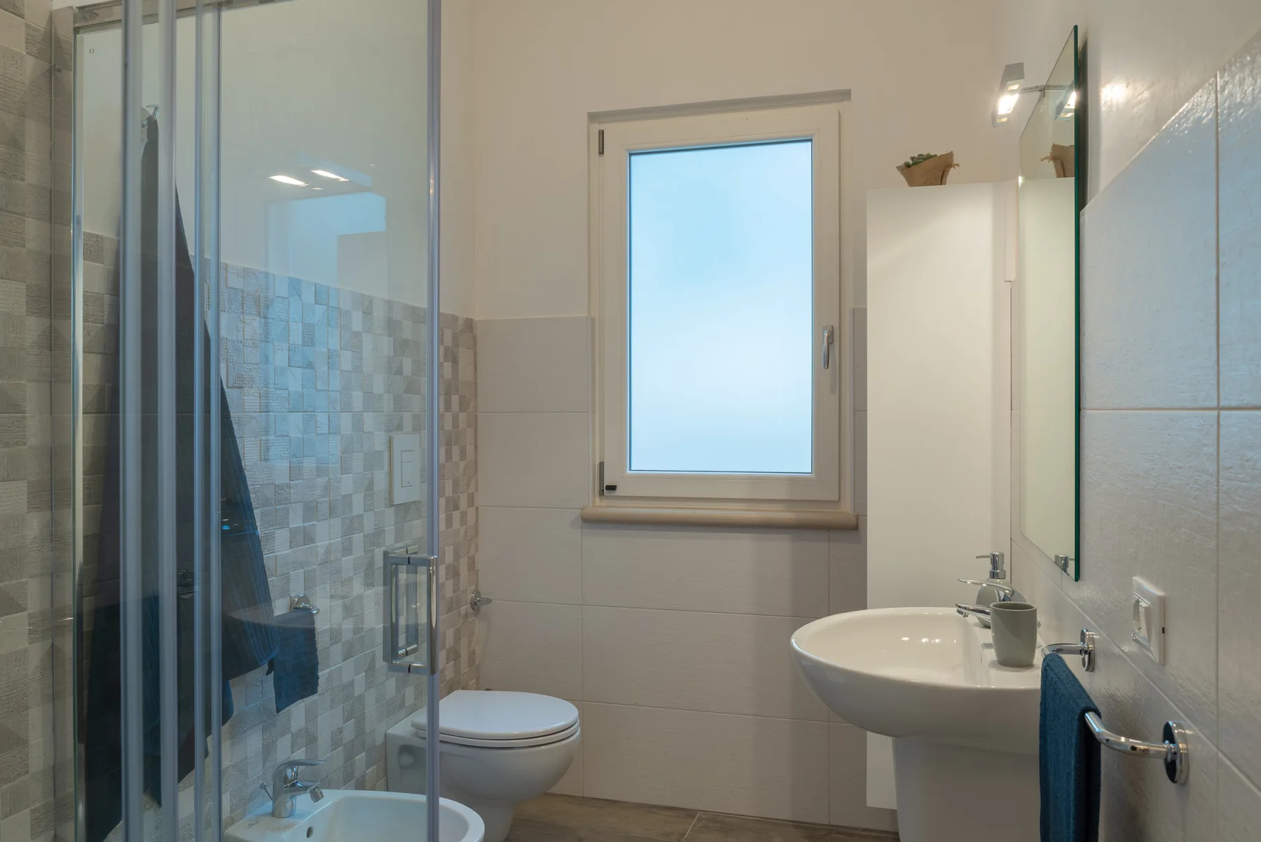 A bathroom with a glass shower, toilet, and sink.