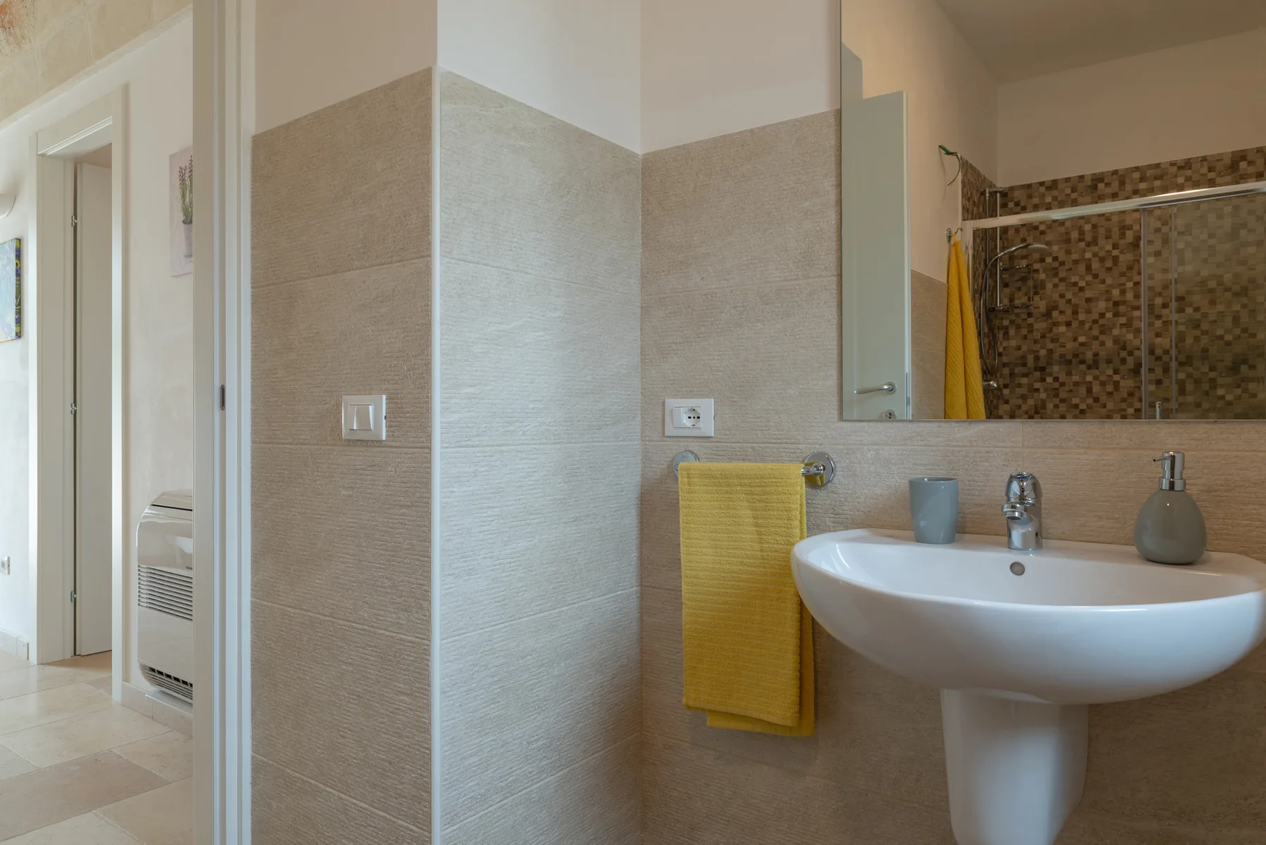 A tiled bathroom with a sink, mirror, and shower area.