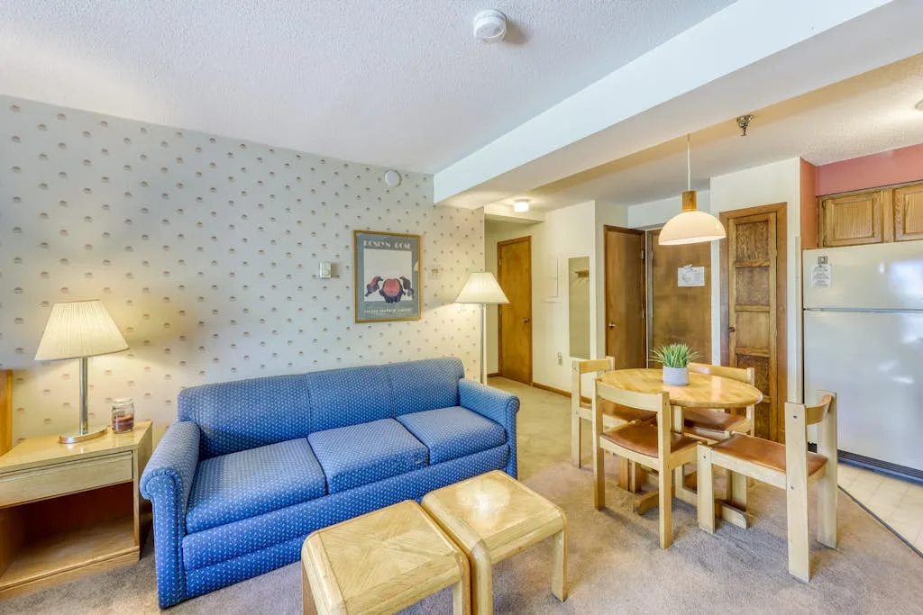 A living and dining area with blue seating and a wooden dining table.