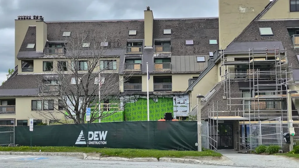 A multi-story building with a green construction fence along the street.