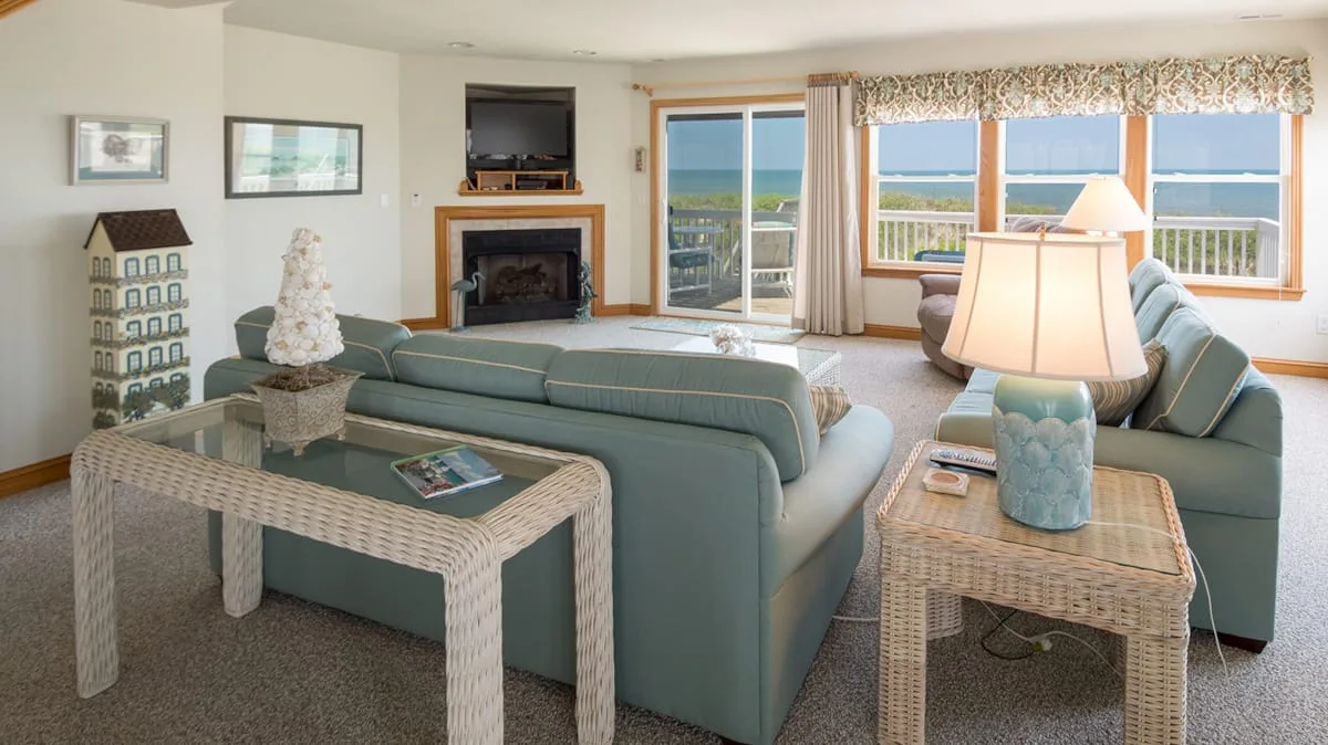 A living room with seating and large windows overlooking the water.