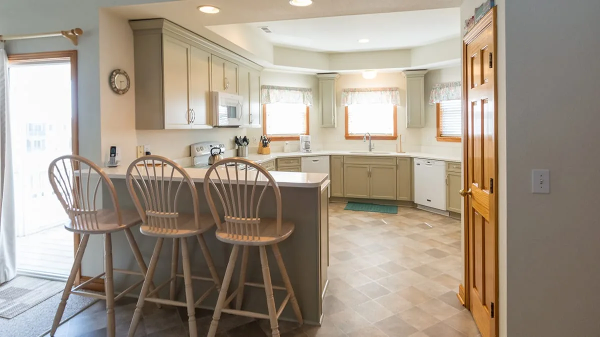 A bright kitchen with a peninsula counter and wooden stools.