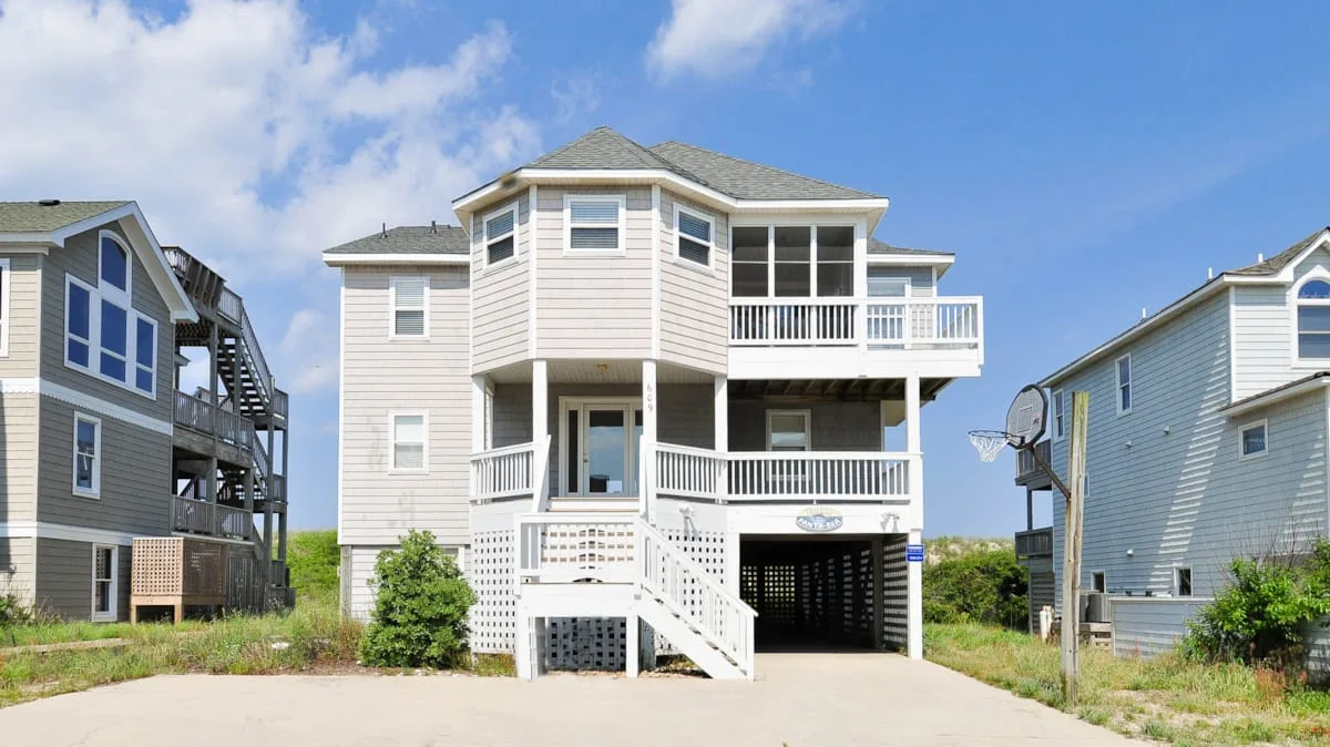 A large coastal-style house with white balconies and exterior stairs.
