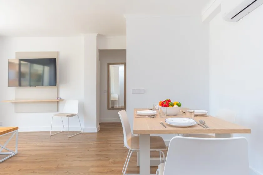 A dining area with a set table beside a wall-mounted television.