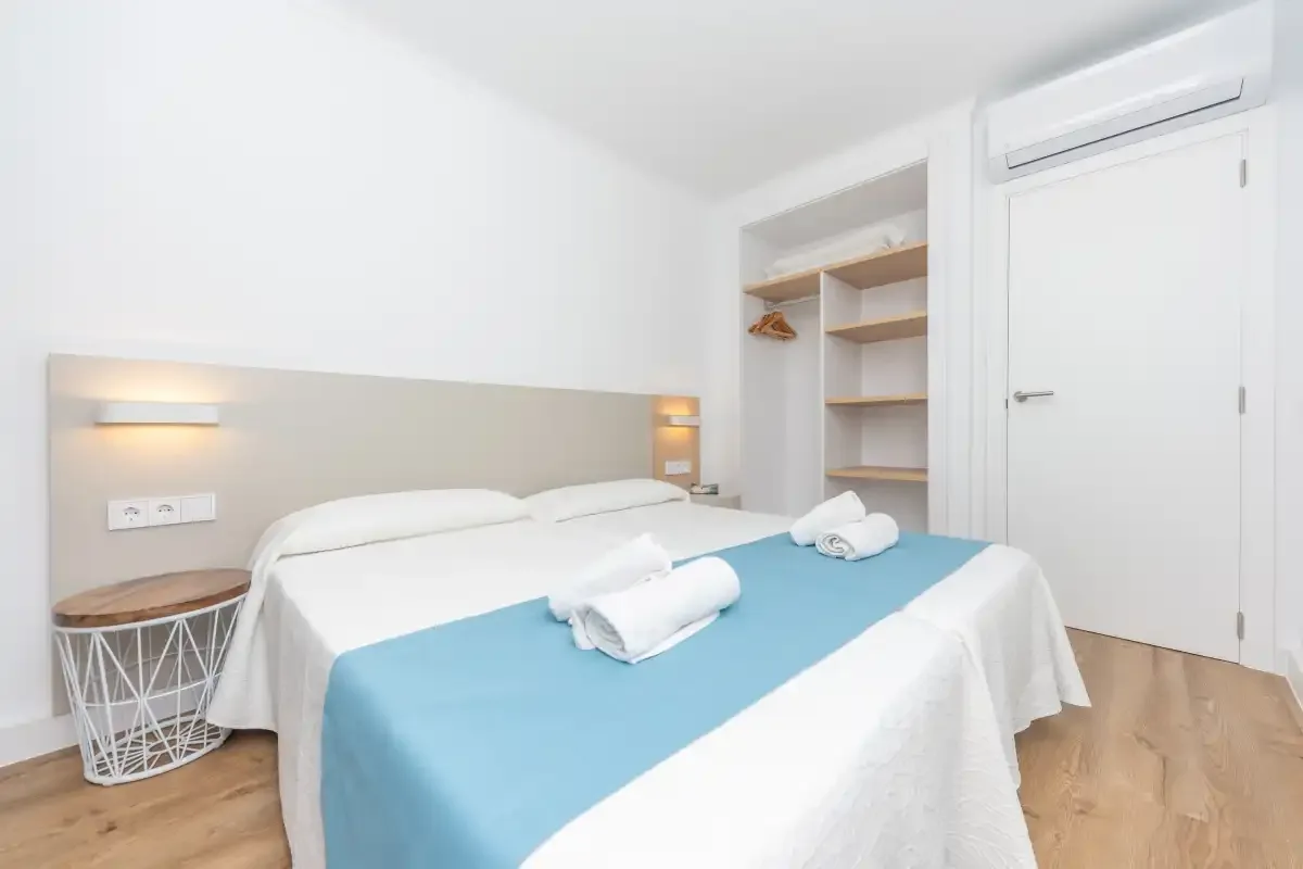 A bedroom with a double bed, blue bedding, and open shelving.