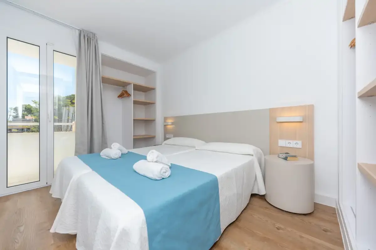 A bright bedroom with a double bed and blue bed runner.