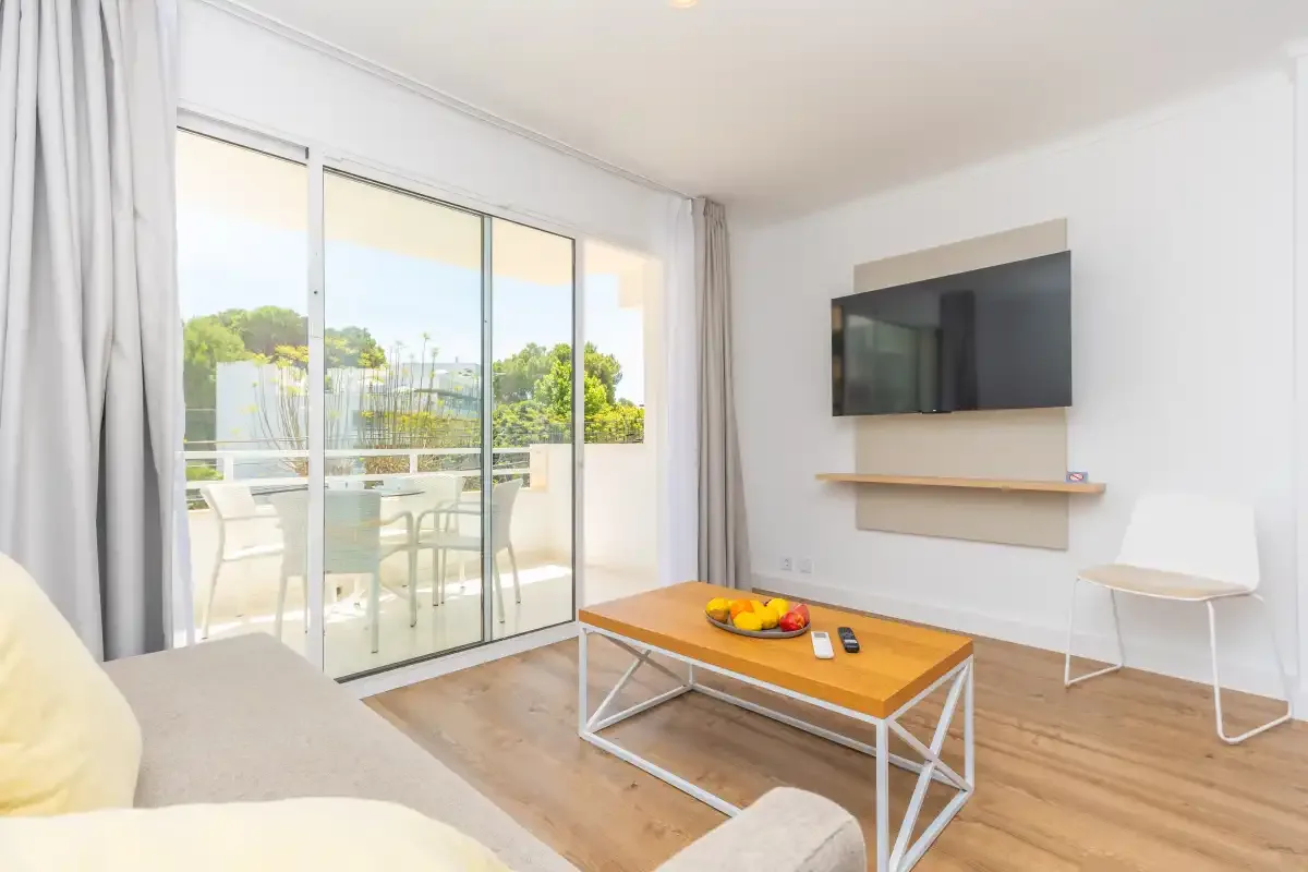 A bright living room with a coffee table and sliding glass doors opening onto a terrace.