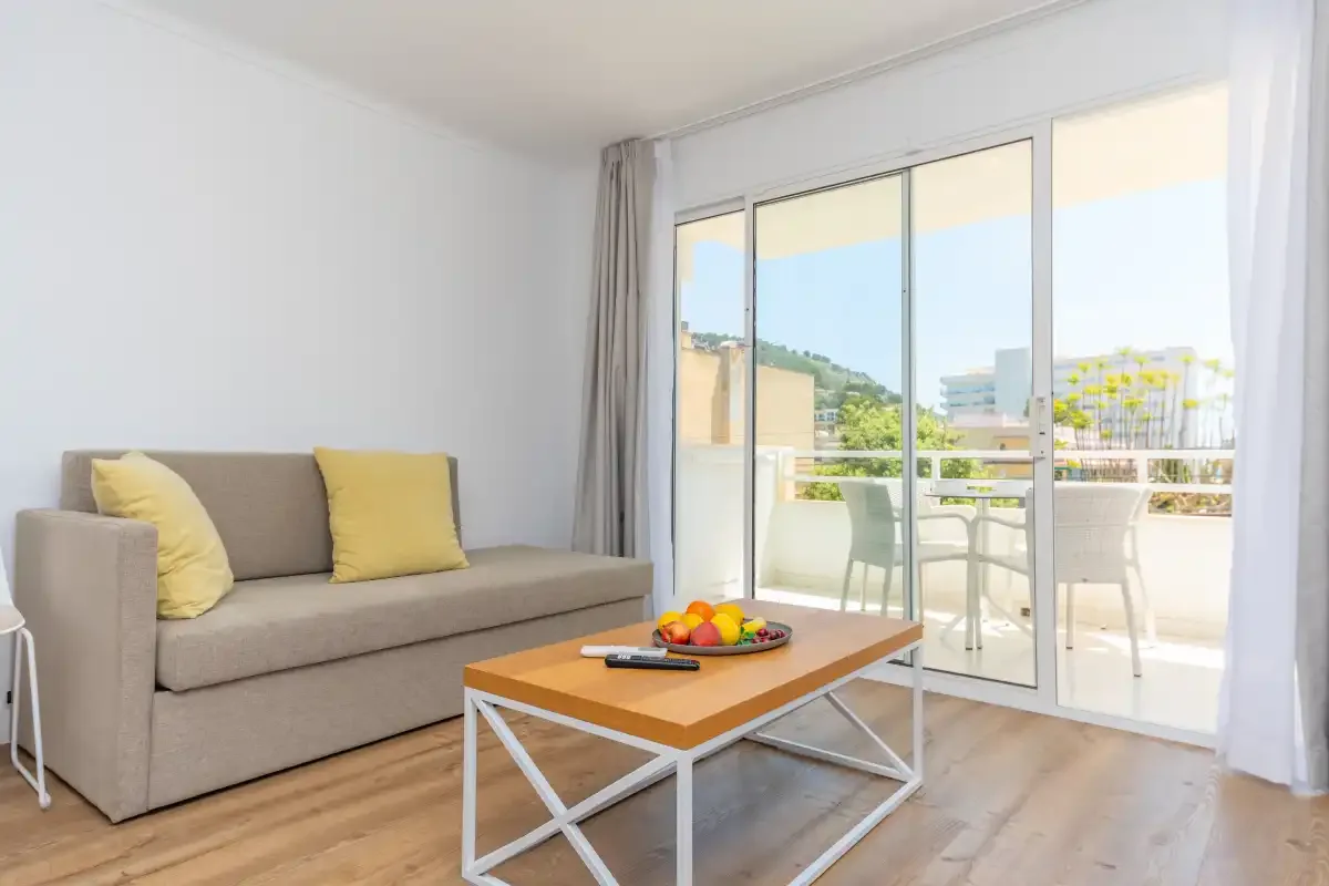 A bright living room with seating, a coffee table, and sliding glass doors to a balcony.