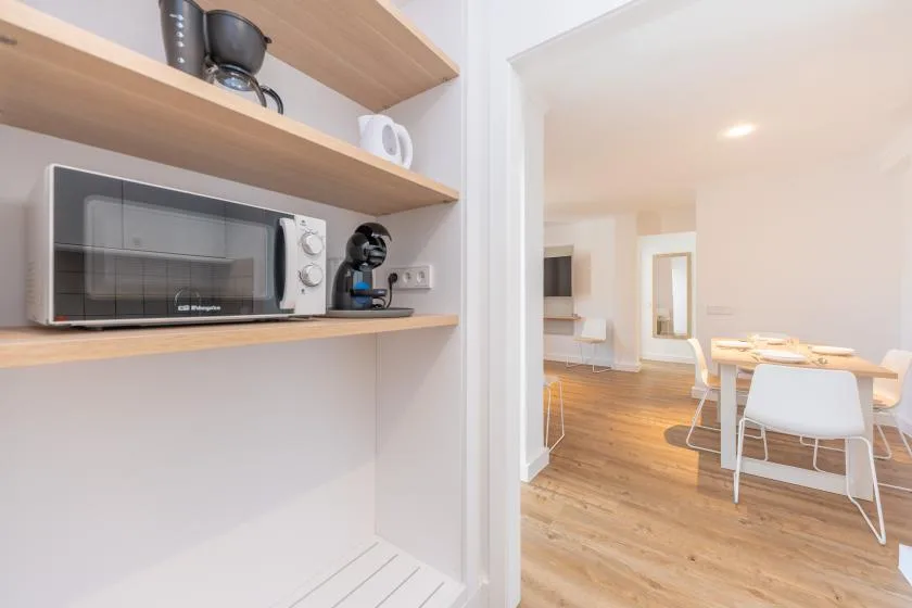 A kitchenette with a microwave and coffee maker opens onto a dining area.