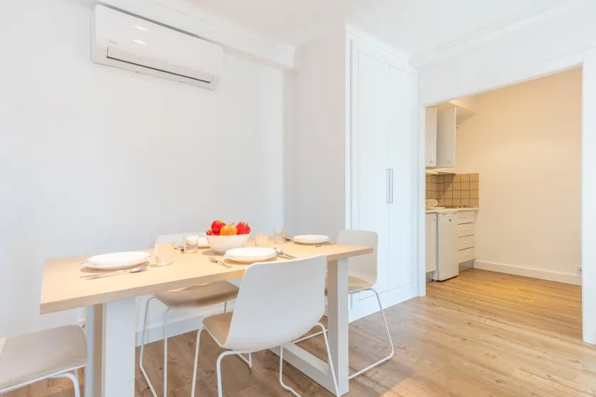 A dining area with a set table beside an open kitchen.