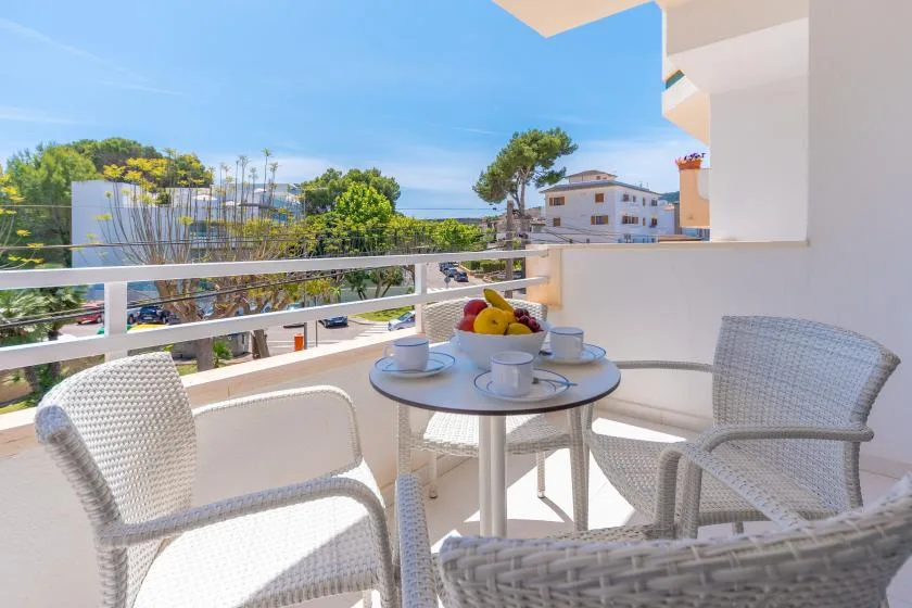 A balcony seating area with a small table overlooking trees and nearby buildings.