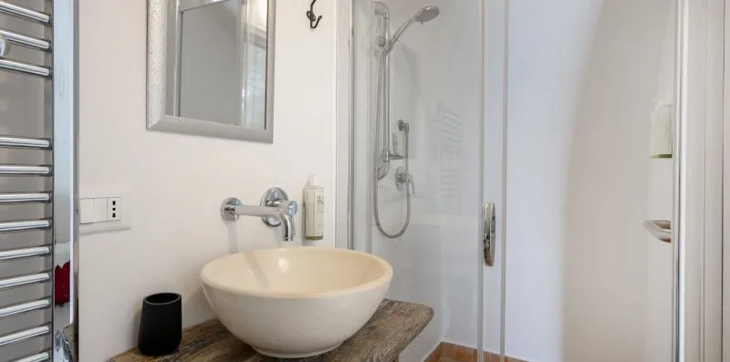 A bathroom vanity with a vessel sink and glass shower.