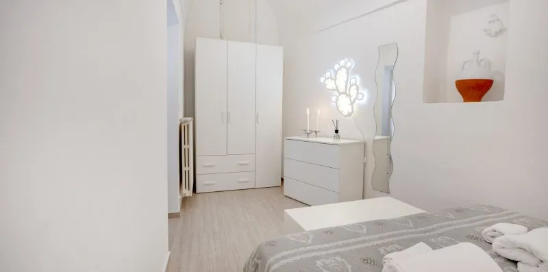 A bright bedroom with a bed, wardrobe, and dresser.