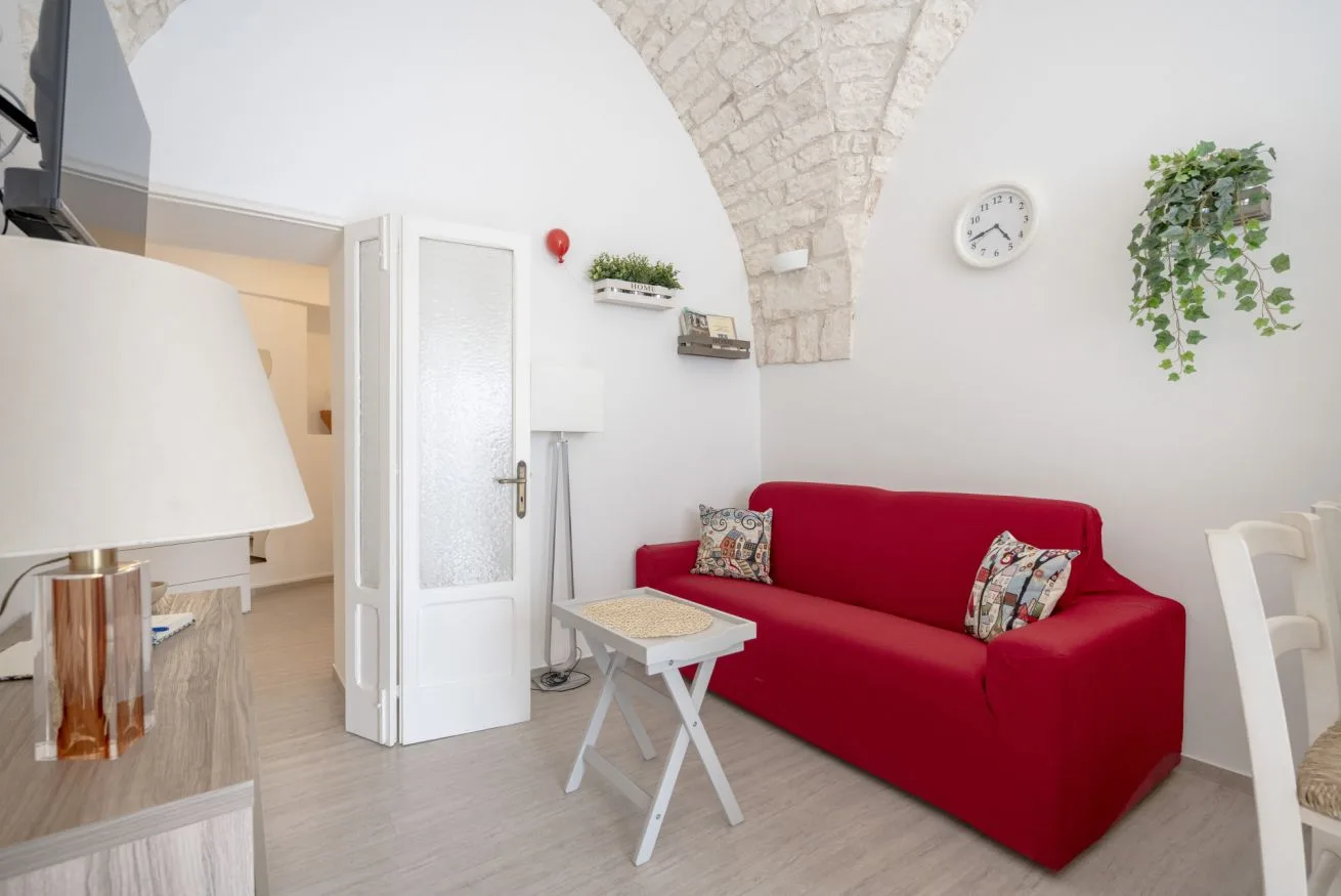 A living room with red seating beneath a stone arch.