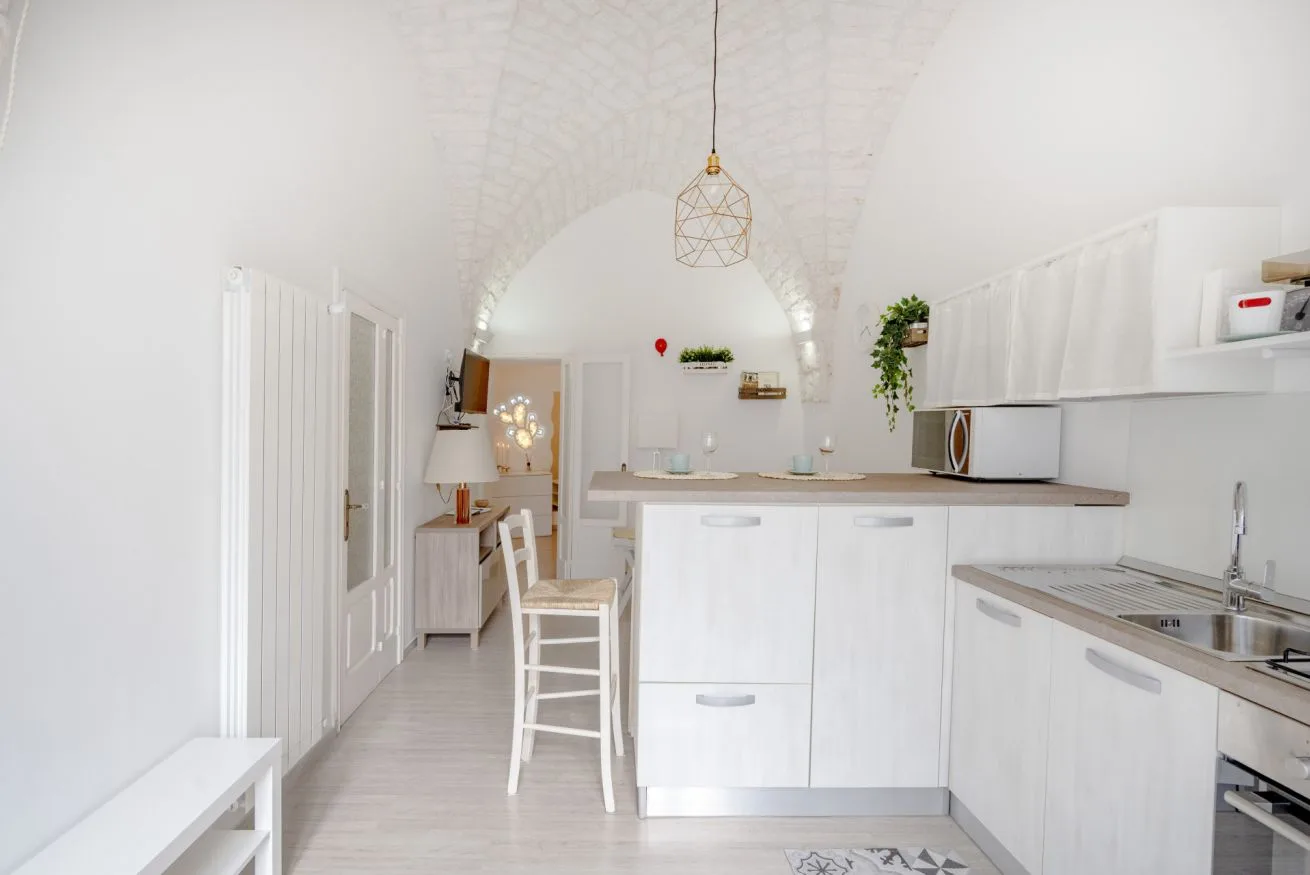 A bright white kitchen with a long counter and a small dining area.