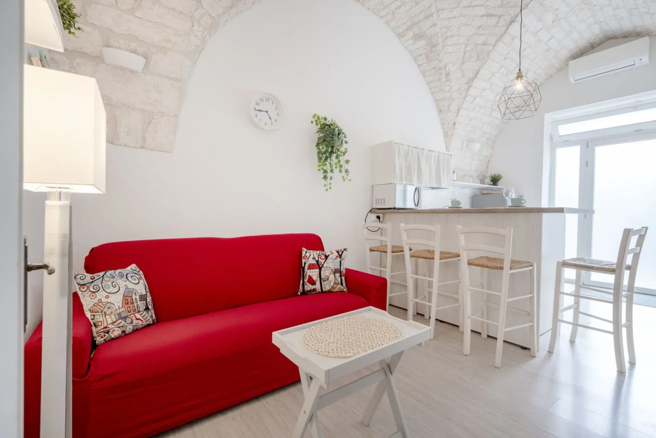 A bright living area with red seating beside a small breakfast bar.