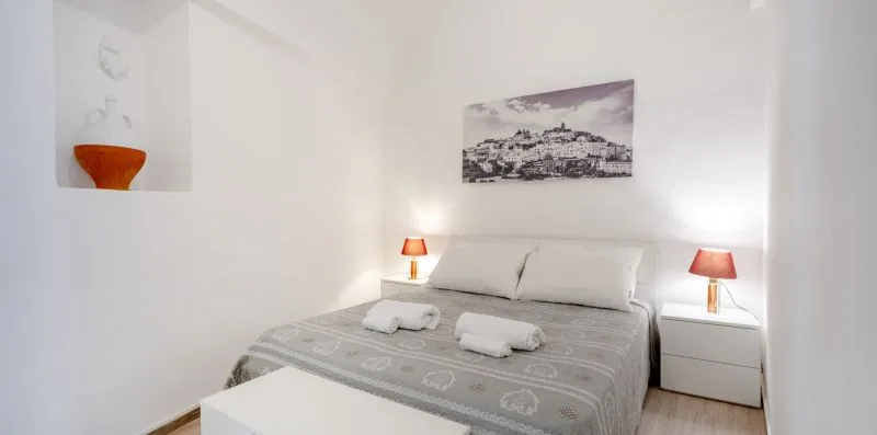 A bedroom with a double bed, bedside tables, and lamps.