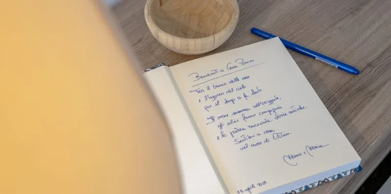 A handwritten note rests on a desk beside a blue pen and small wooden bowl.