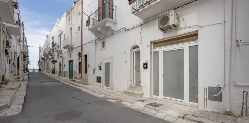 A narrow paved street lined with white buildings and balconies.
