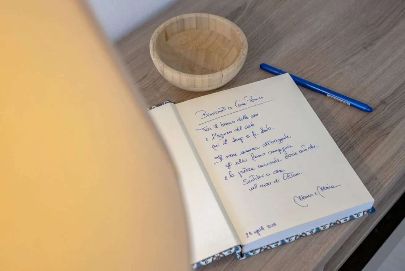 An open guestbook and pen rest on a tabletop beside a small wooden bowl.