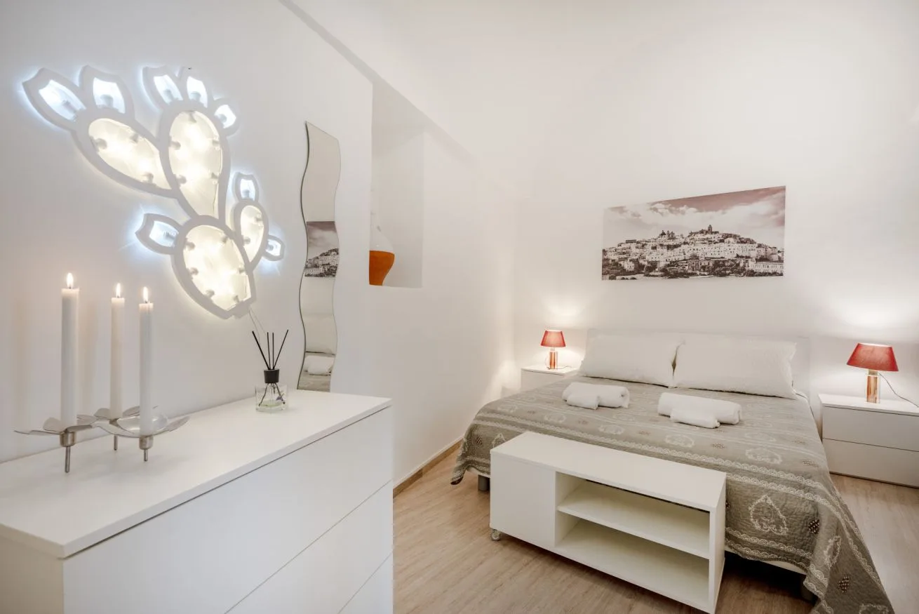 A bedroom with a bed, bedside lamps, and a white dresser.