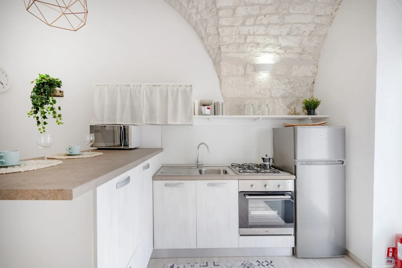 A compact kitchen with white cabinetry, a countertop, and stainless steel appliances.