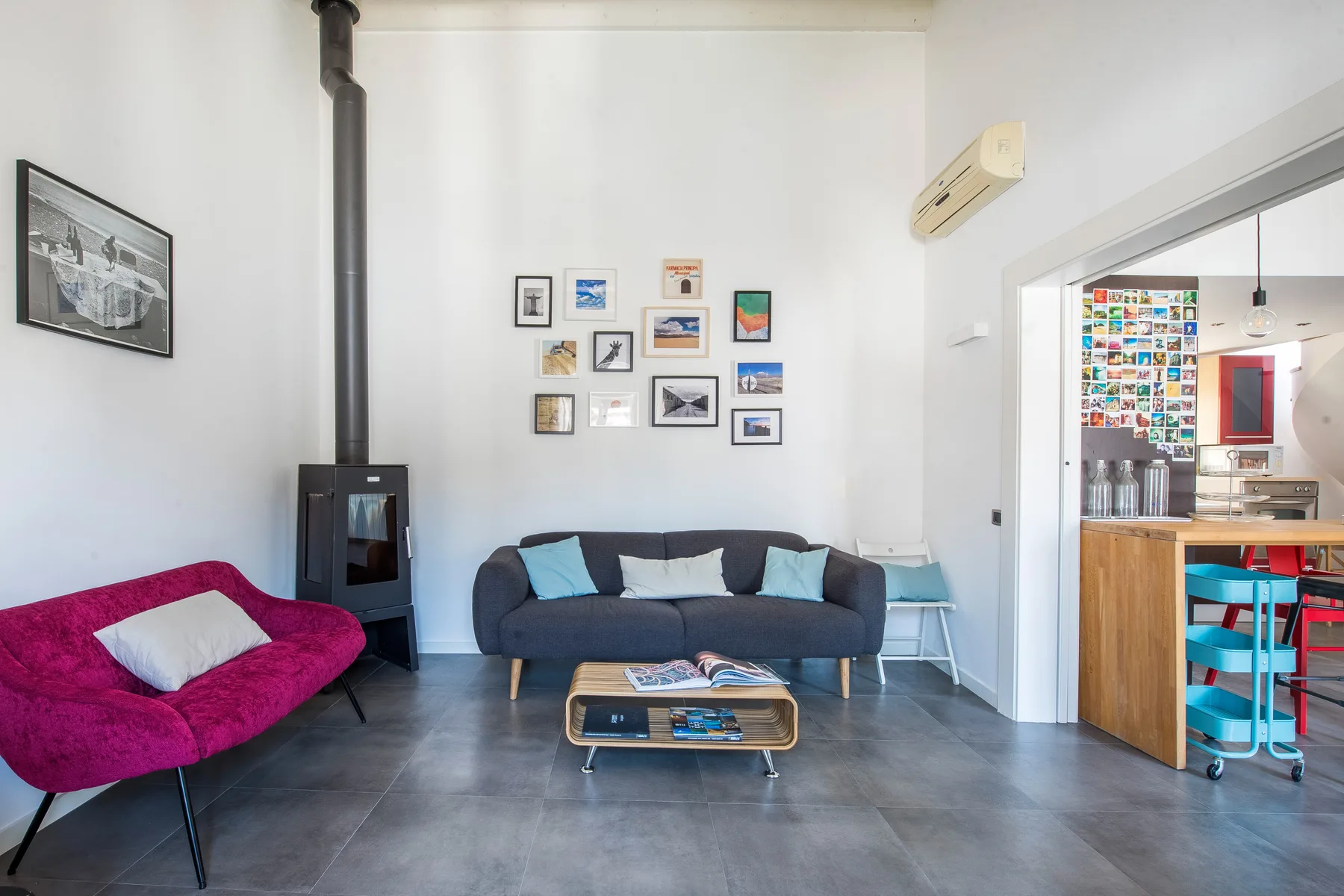 Una sala de estar con asientos, cuadros enmarcados y una estufa junto a la pared.