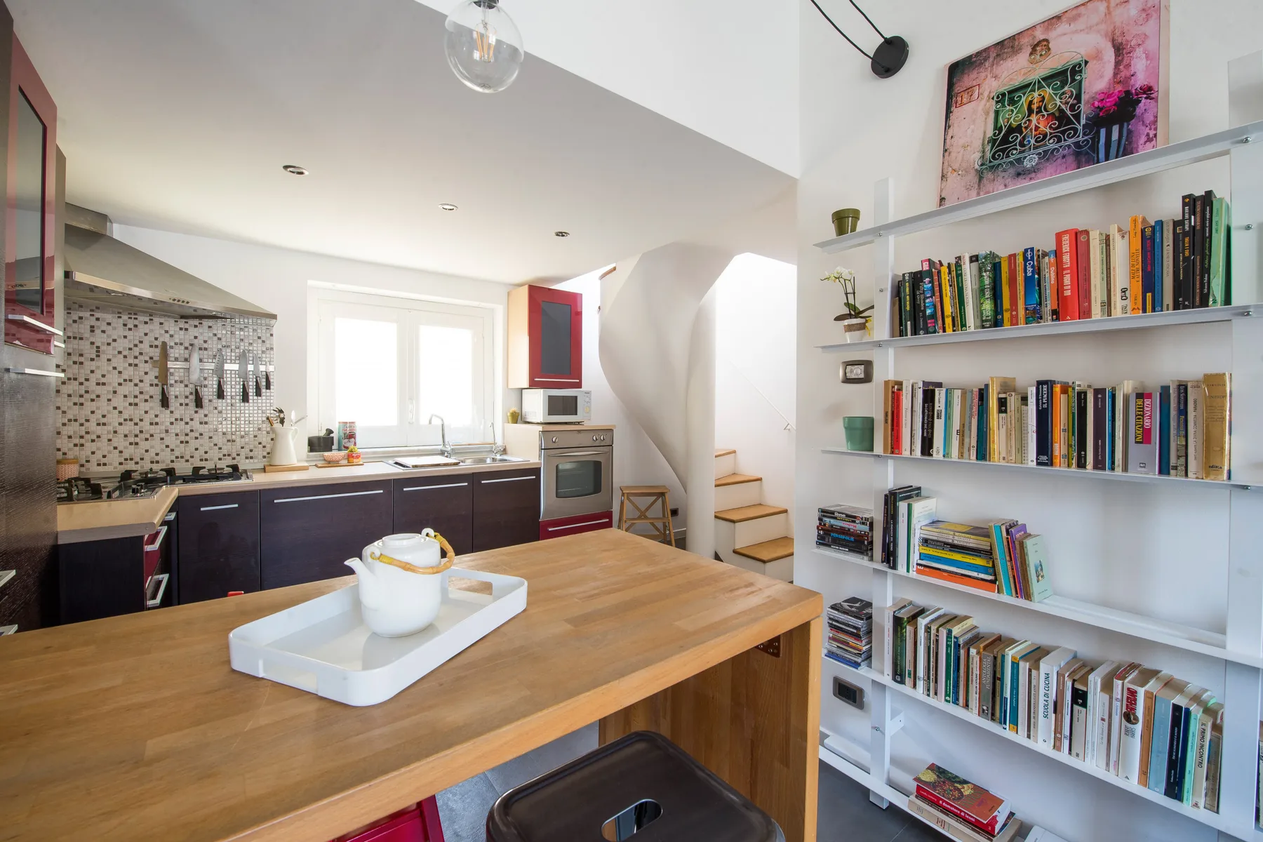 Una cocina y comedor abiertos con una mesa de madera y estanterías.