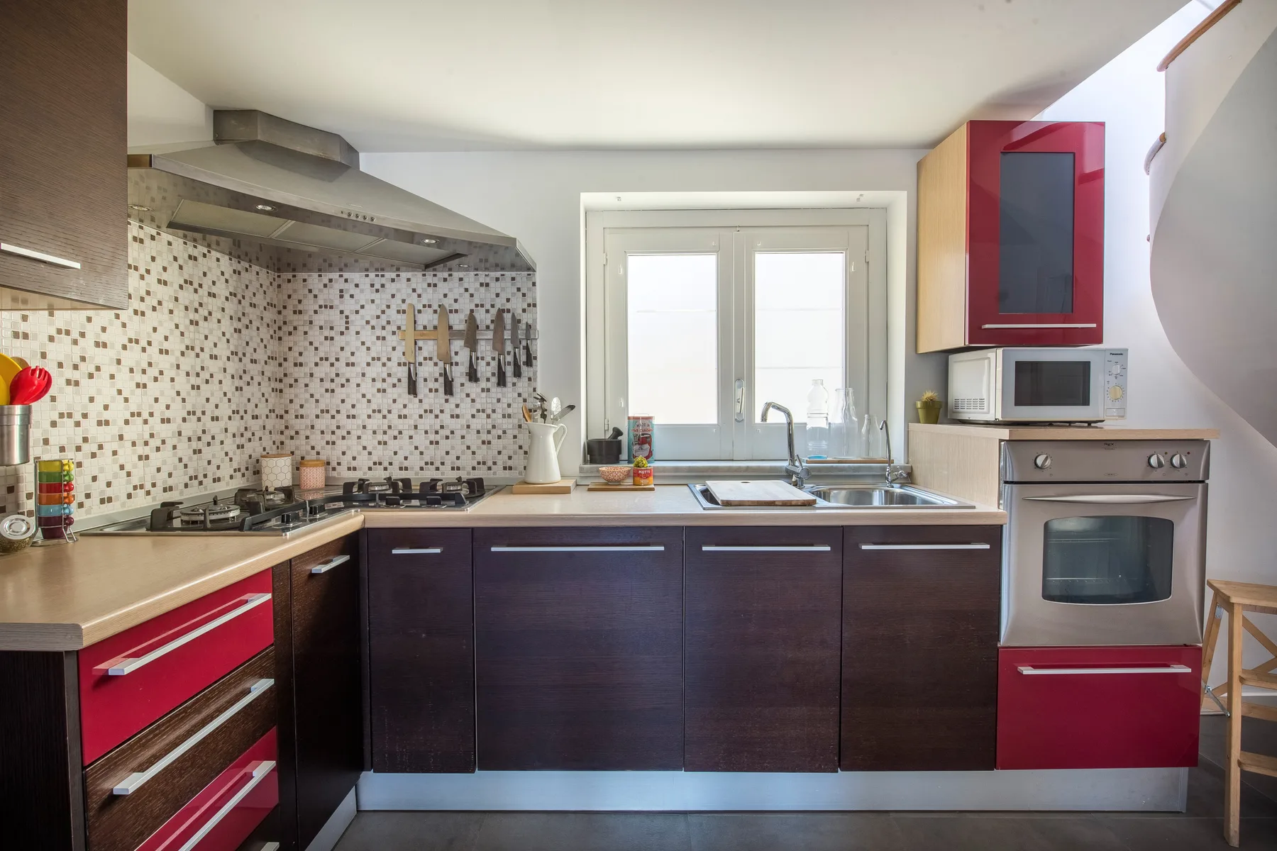 Una cocina con gabinetes oscuros, un salpicadero de azulejos y una ventana sobre el fregadero.