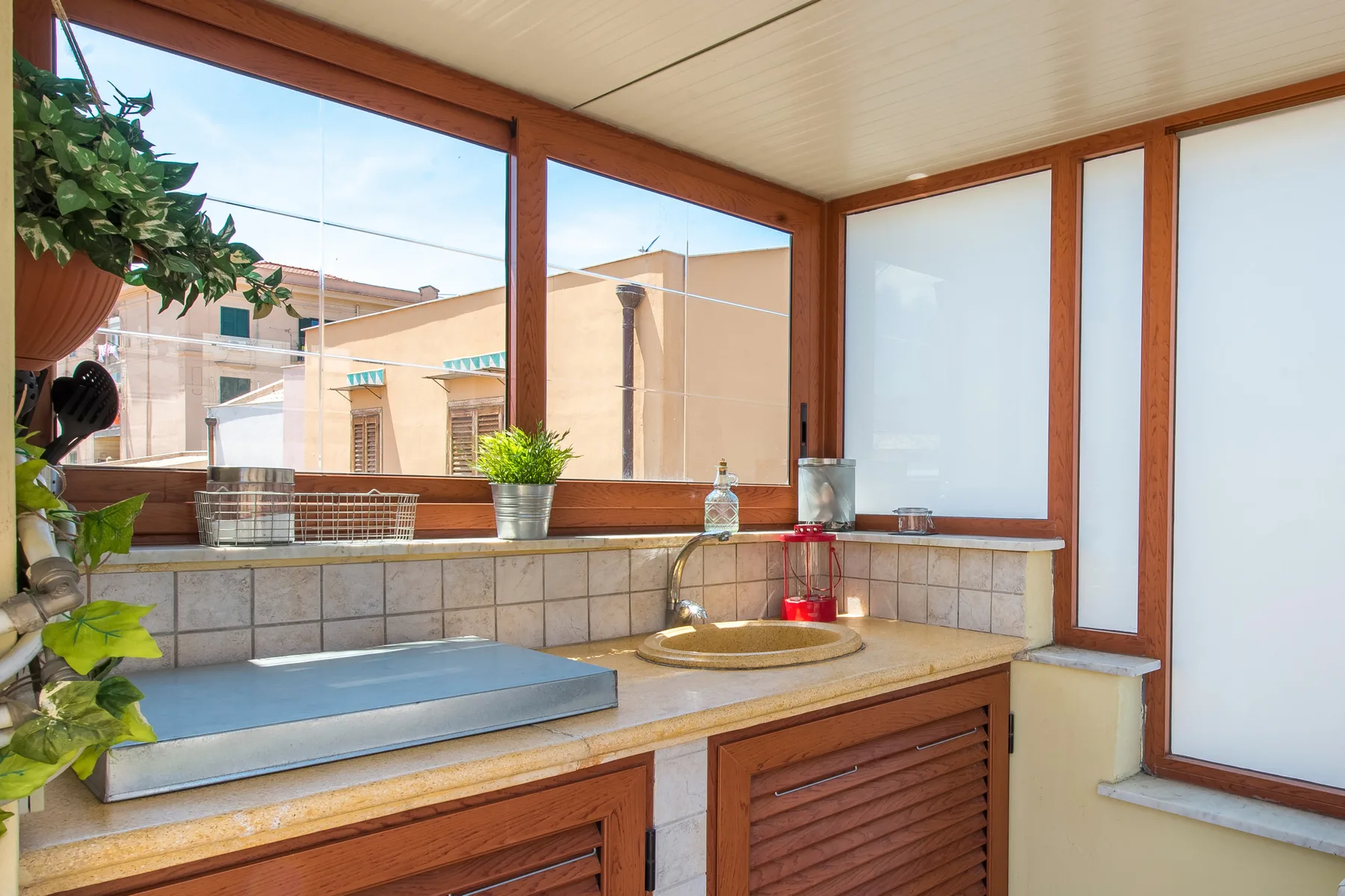 Un tocador de baño está bajo grandes ventanas, con un lavabo y una encimera.