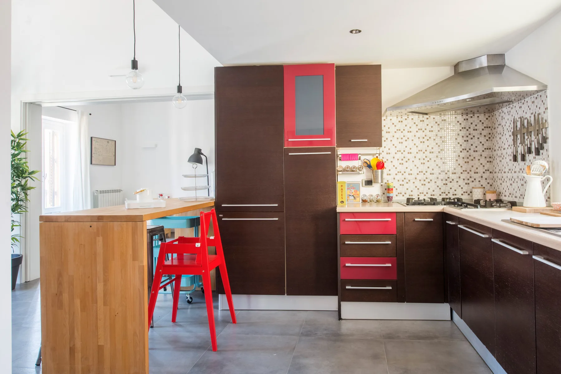 Una cocina moderna con gabinetes oscuros, un salpicadero de azulejos y una barra de madera.