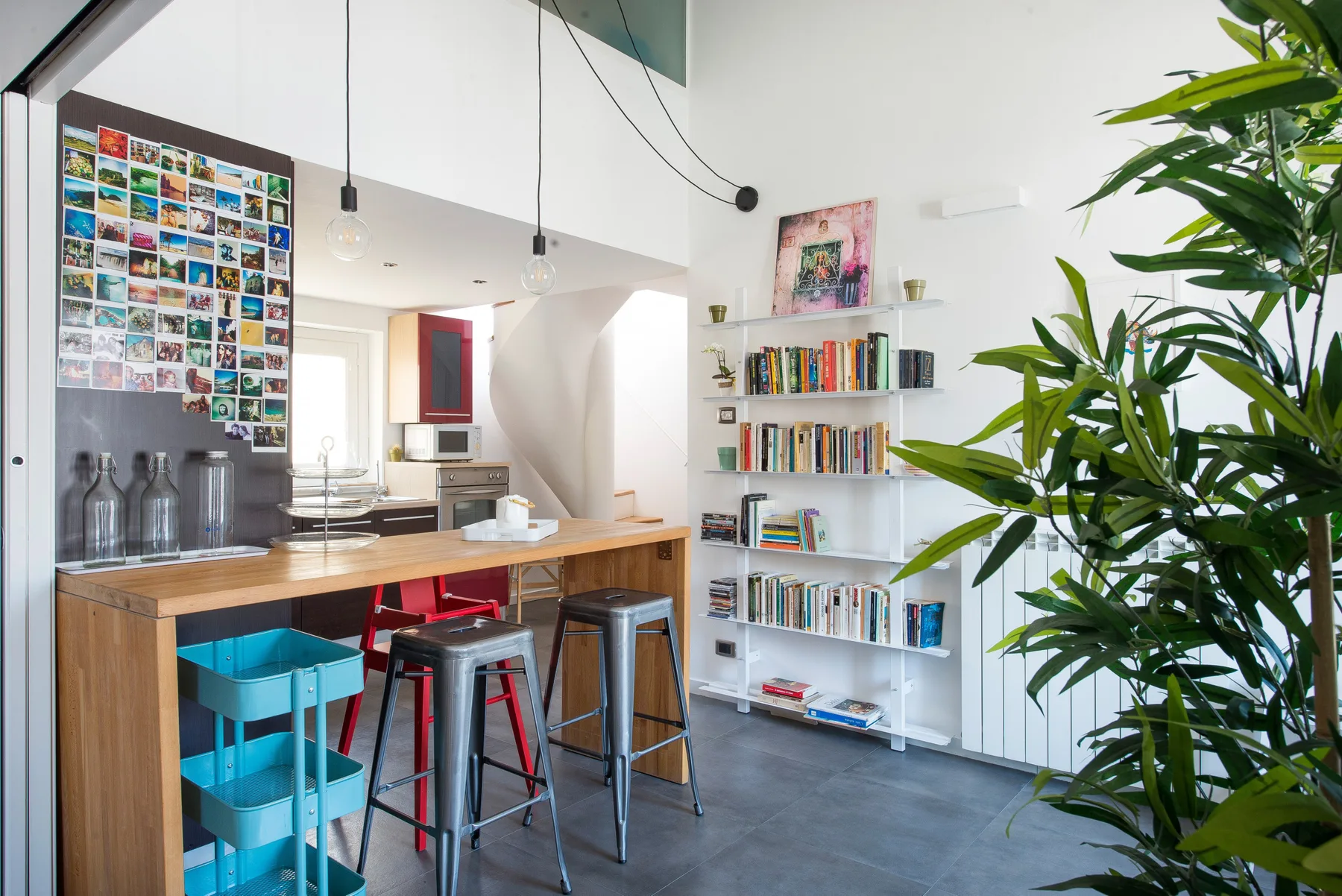 Una luminosa cocina-comedor abierta con una barra de madera y estanterías.