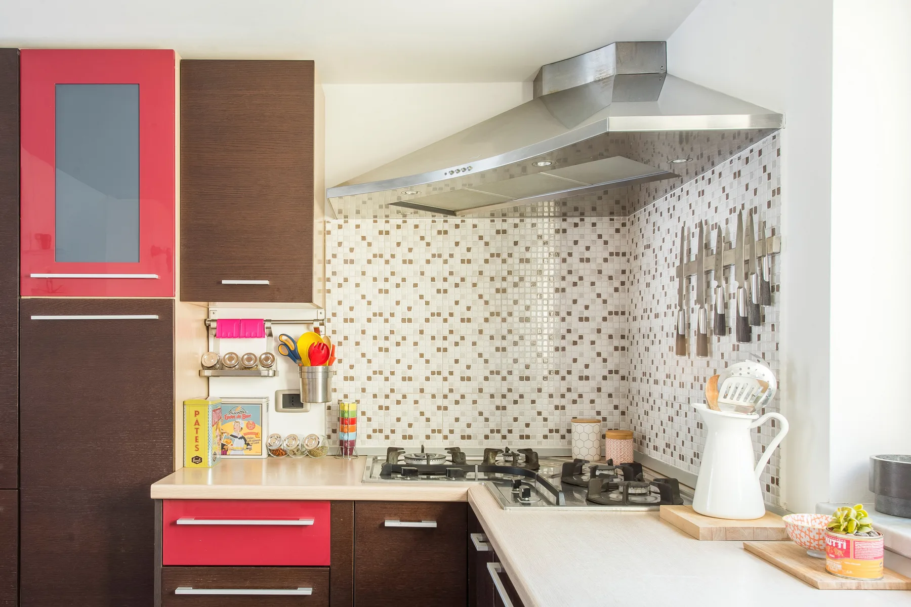 Una cocina con placa de cocción, campana extractora y salpicadero de azulejos.