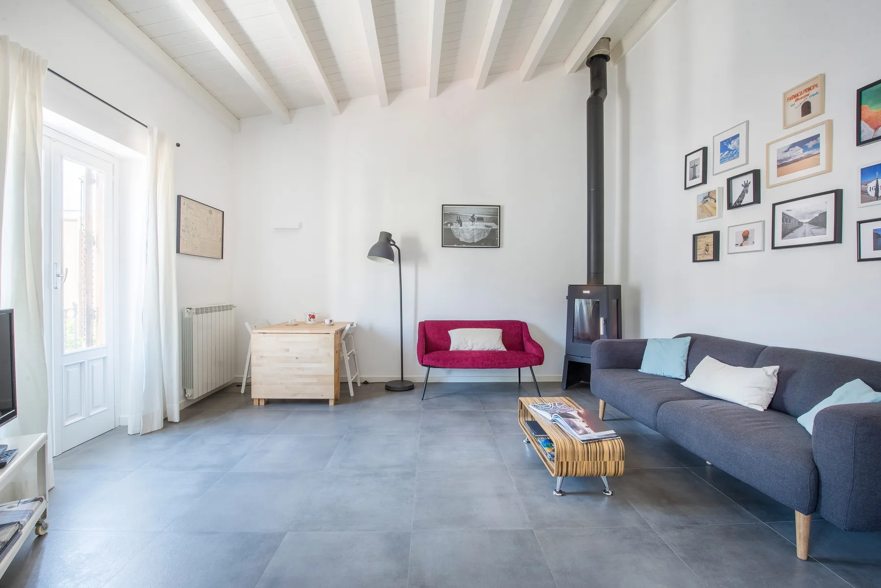 Una sala de estar luminosa con asientos, una mesa de centro y cuadros en la pared.