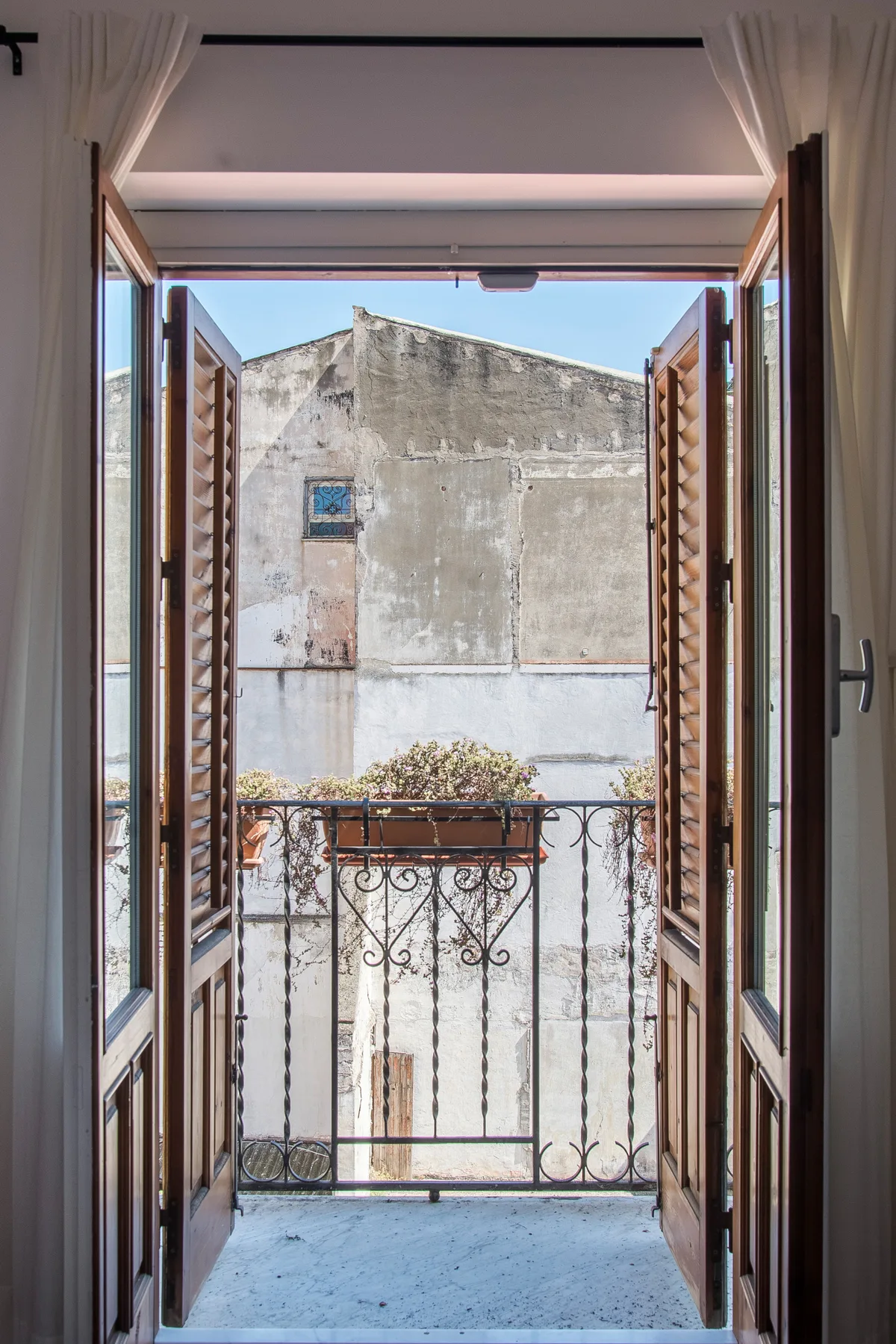Una ventana abierta da a un edificio vecino y a una pequeña barandilla de balcón.