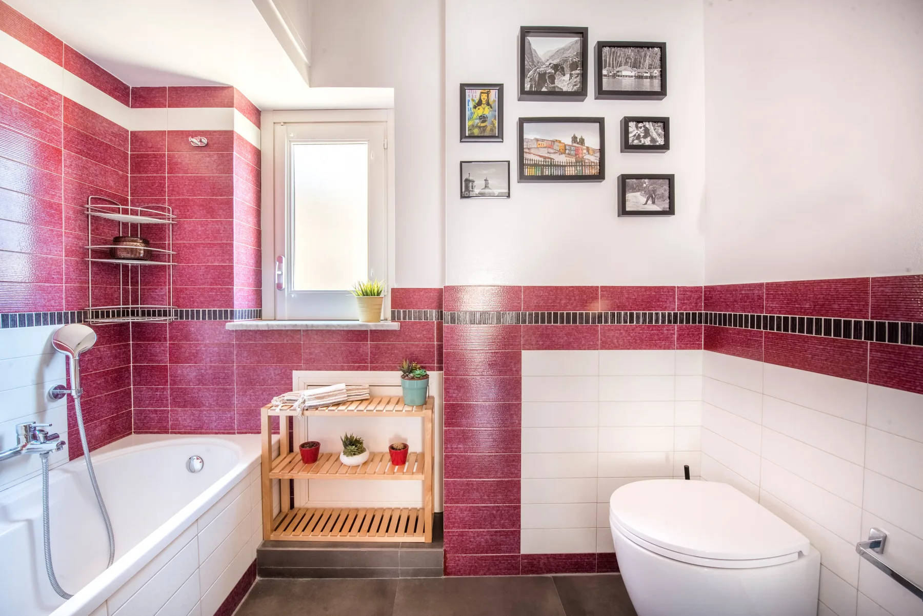 Un baño con bañera, inodoro y una pequeña estantería de madera.