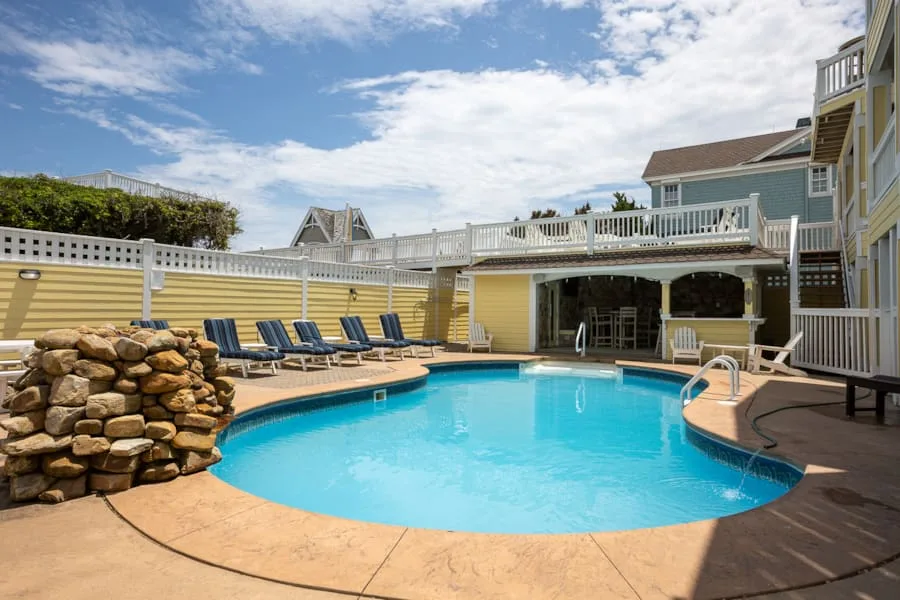 Una piscina al aire libre está junto a una terraza elevada de madera y asientos.