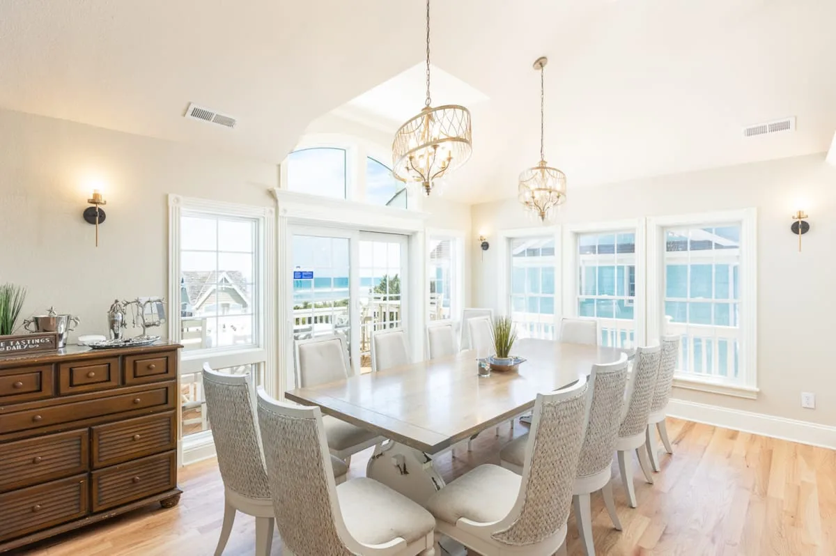 Un comedor luminoso con una mesa larga junto a grandes ventanas.