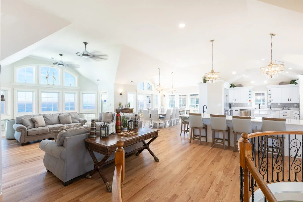 Una sala abierta y cocina con comedor y grandes ventanas.